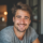 Homme souriant avec barbe dans un intérieur cosy.