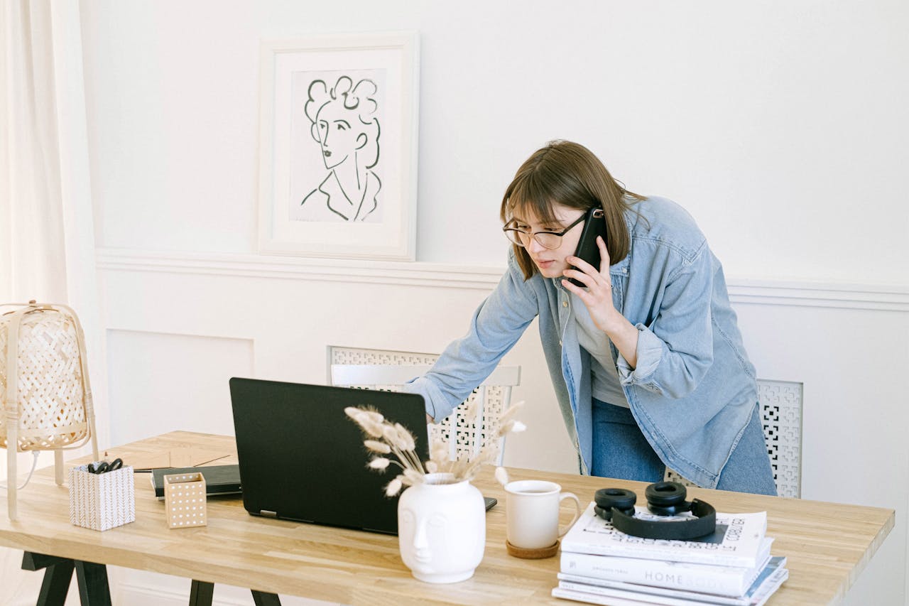 about-03 Woman multitasking with laptop and phone in modern home office setting.